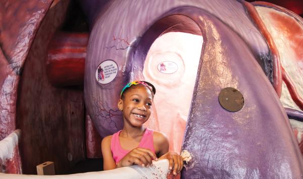 Young girl smiling, walking through The Giant Heart at the Franklin Institute.