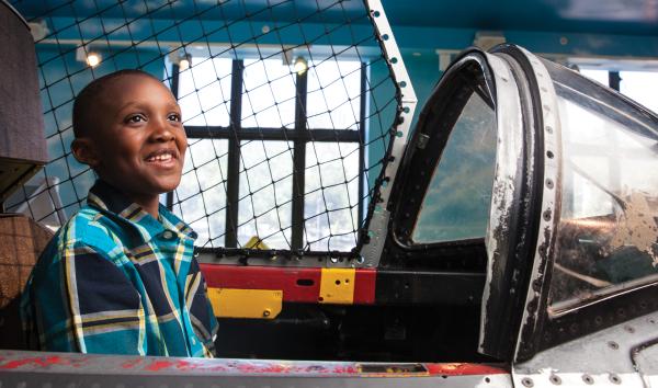 A young boy sits in the cockpit of the plane that hangs from the ceiling in the permanent exhibit The Franklin Airshow