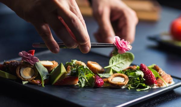 Seravezza Events catering staff places an edible flower atop a plate