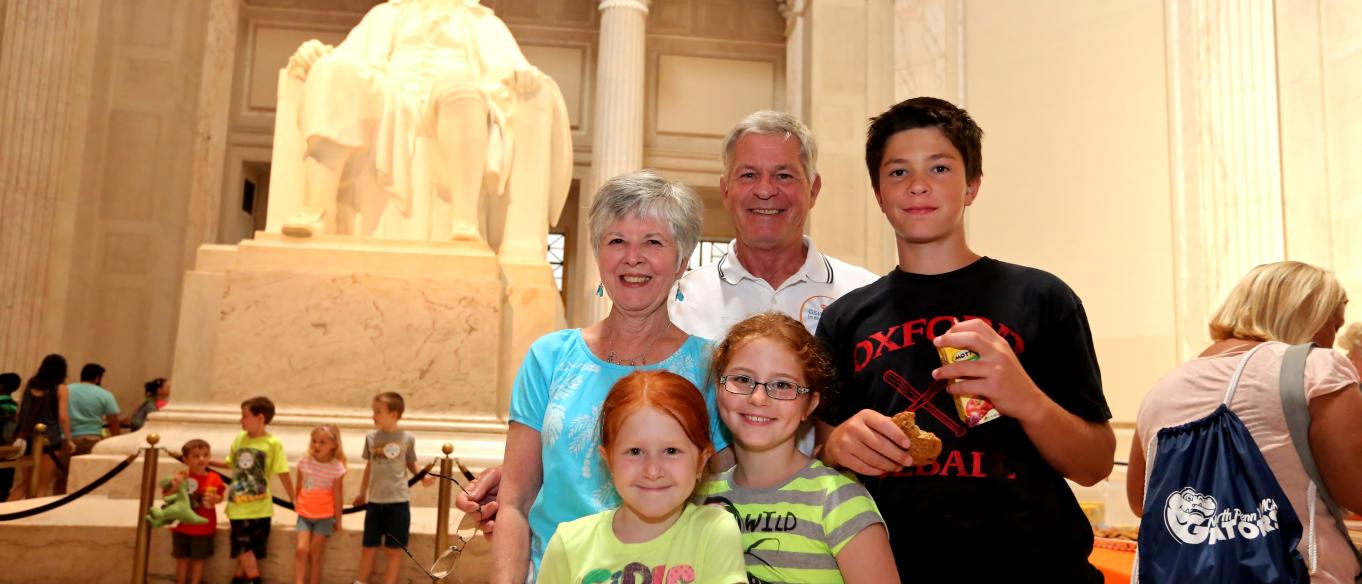 A family standing in front of the Benjamin Franklin Memorial statue at the Franklin Institute.