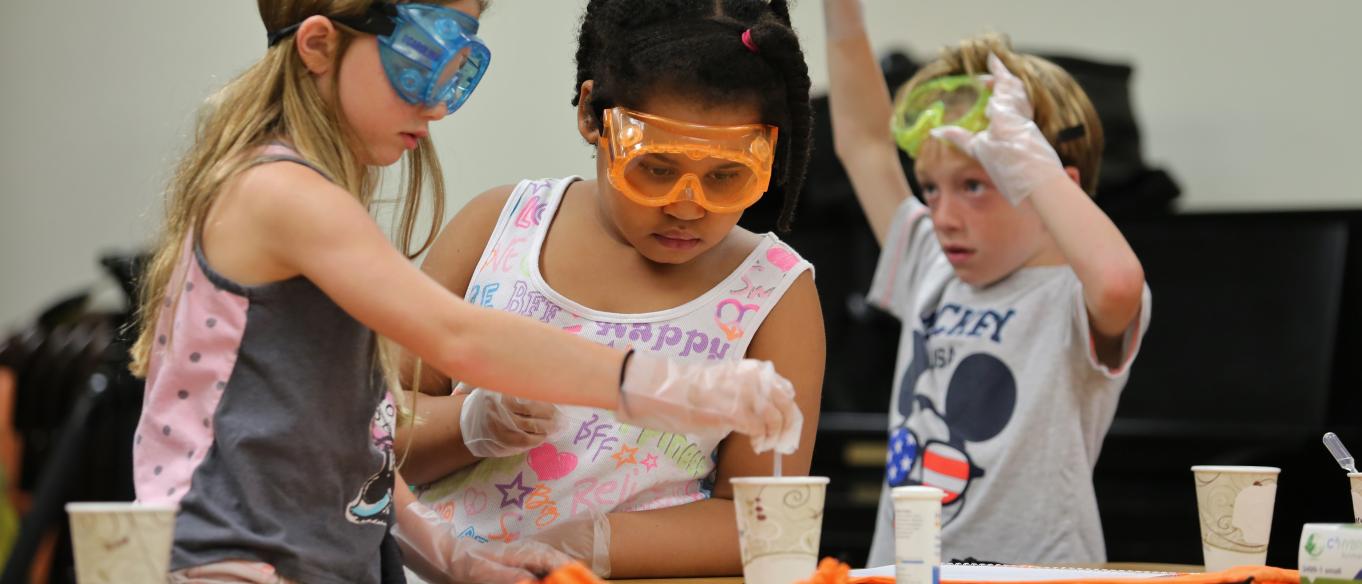Image of three young children wearing goggles doing science activity