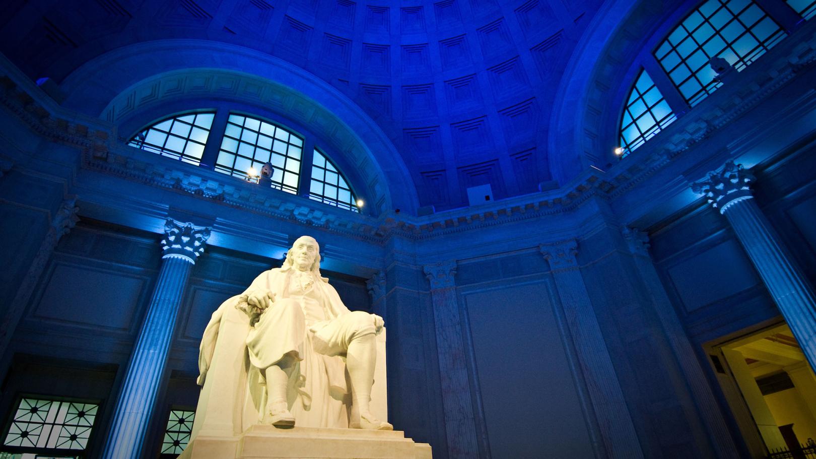 Benjamin Franklin Memorial statue with dramatic dark blue lighting